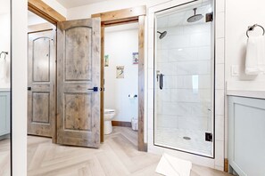 A bathroom with a glass shower enclosure, a toilet, and wooden doors. - Ski-in-ski-out condo - indoor & outdoor pools, sauna, hot tubs, game room, gym, W&D, AC (Park City)