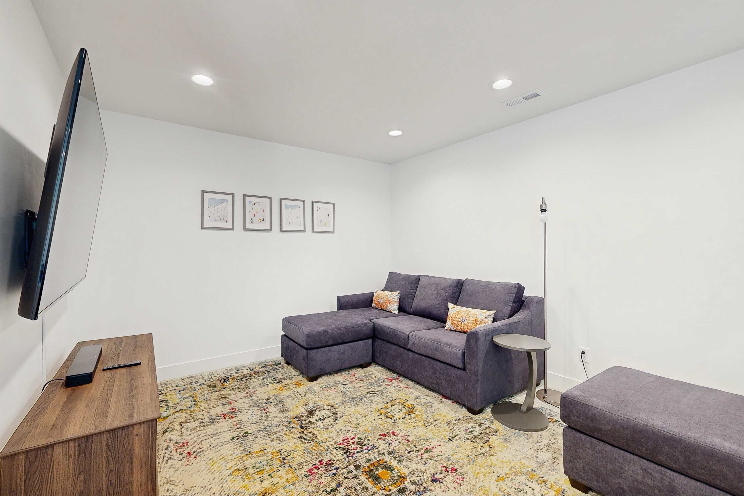 Una sala de estar moderna con un sofá modular, una mesita redonda y un televisor de pantalla plana montado en la pared.