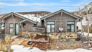 A two-story house with a stone foundation, a patio with a table and chairs, and a satellite dish. - Lovely home with gas fireplaces, patio, hot tub, & WiFi - great location (Park City)