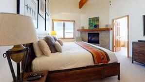 A bedroom with a bed, a lamp, a fireplace, and framed pictures on the wall. - Lovely home with gas fireplaces, patio, hot tub, & WiFi - great location (Park City)