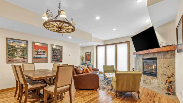 A dining area with a wooden table and chairs, a sofa, and a fireplace. - Lovely home with gas fireplaces, patio, hot tub, & WiFi - great location (Park City)