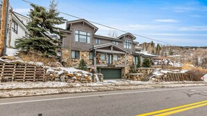 A multi-story residential building with a stone facade, a garage, and a driveway. - Lovely home with gas fireplaces, patio, hot tub, & WiFi - great location (Park City)