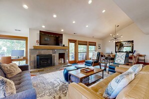 A spacious living room with a fireplace, comfortable seating, and large windows. - Walk to lifts & Main St condo with hot tub, heated garage, & mountain view (Park City)