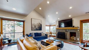 A spacious living room with a fireplace, a large TV, and a balcony with a view. - Walk to lifts & Main St condo with hot tub, heated garage, & mountain view (Park City)