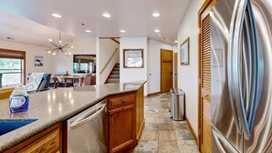 A kitchen with a stainless steel refrigerator, wooden cabinets, a dishwasher, and a countertop with a dish soap bottle. - Walk to lifts & Main St condo with hot tub, heated garage, & mountain view (Park City)