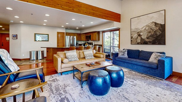 A spacious living area with a sofa, coffee table, and blue accent pieces. - Walk to lifts & Main St condo with hot tub, heated garage, & mountain view (Park City)