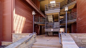 A multi-level parking garage with a central staircase, railings, and a light fixture. - Walk to lifts & Main St condo with hot tub, heated garage, & mountain view (Park City)