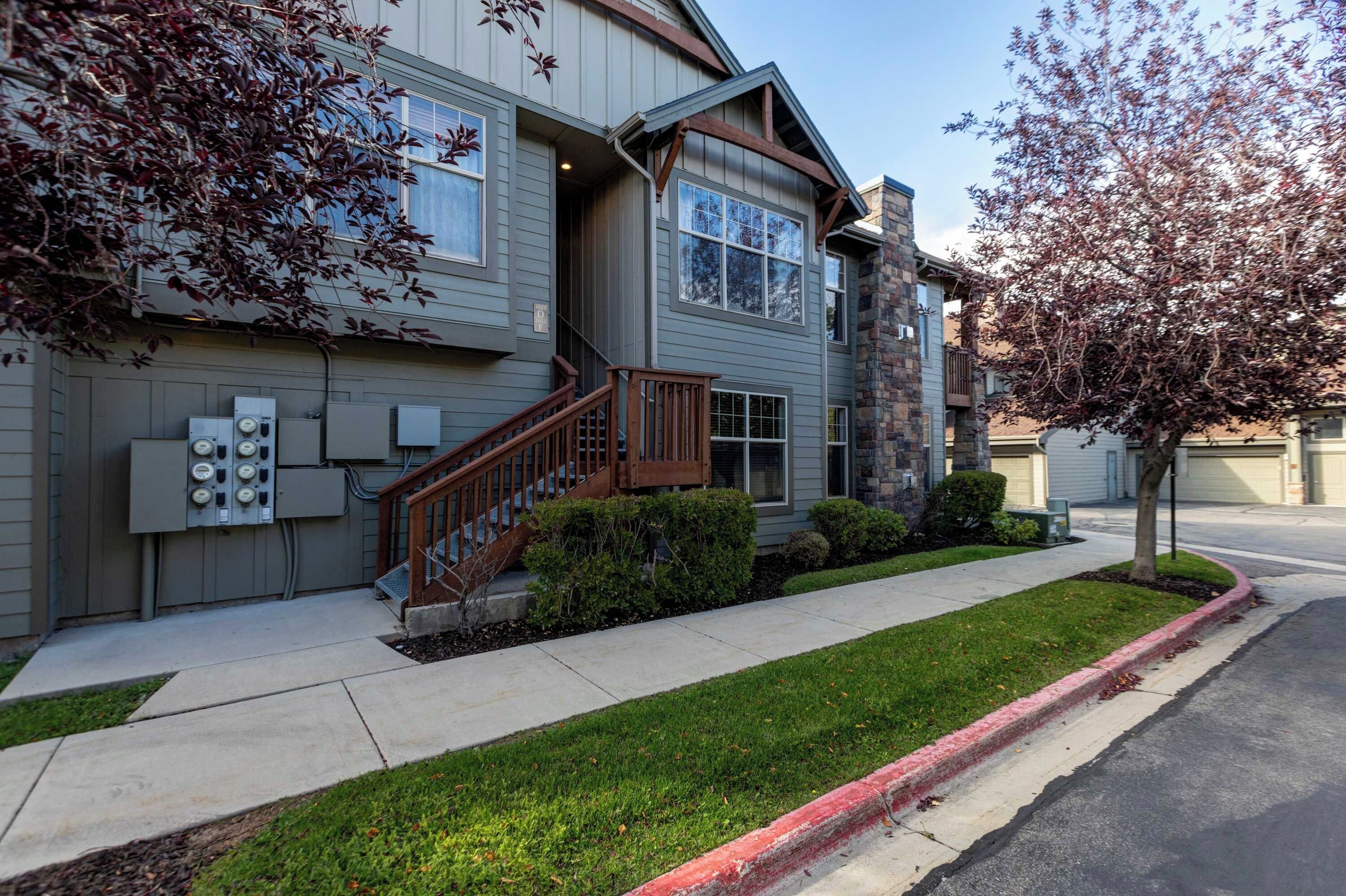 A two-story residential building with a front entrance, a staircase, and a small front yard.