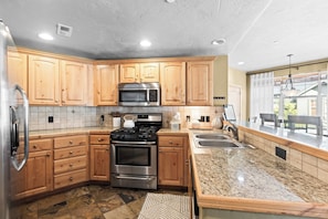 A modern kitchen with wooden cabinets, stainless steel appliances, and a granite countertop. - Spacious Redstone Home with Fireplace, Patio & Walk to Dining (Park City)