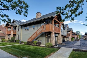 A multi-story residential building with a stone chimney, wooden balconies, and a covered front porch. - Spacious Redstone Home with Fireplace, Patio & Walk to Dining (Park City)