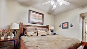 A bedroom with a bed, nightstands, a ceiling fan, and framed pictures on the wall. - Spacious Redstone Home with Fireplace, Patio & Walk to Dining (Park City)