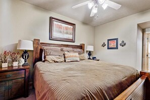 A bedroom with a bed, nightstands, a ceiling fan, and framed pictures on the wall. - Warm spacious home base at Redstone - walk to shops & dining (Park City)