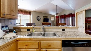 A kitchen with granite countertops, wooden cabinets, a double sink, and a dishwasher. - Spacious Redstone Home with Fireplace, Patio & Walk to Dining (Park City)