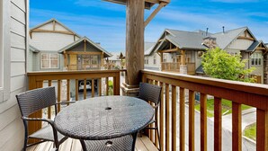 A wooden deck with a round table and chairs, overlooking a row of houses with gabled roofs. - Spacious Redstone Home with Fireplace, Patio & Walk to Dining (Park City)