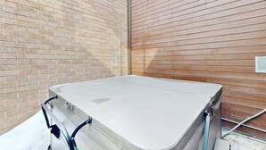 Ein Zimmer mit Matratze auf dem Boden, einem Metallbettgestell, einer Ziegelwand und einer Holzwand.