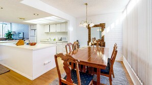 Eine moderne Küche mit weißen Schränken, einer zentralen Kochinsel und einem Essbereich mit Holztisch und Stühlen.