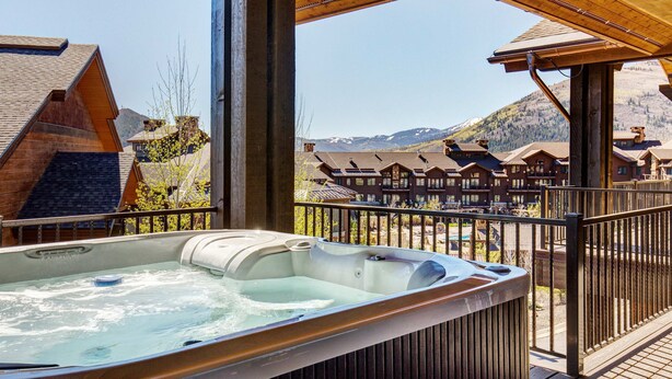 A hot tub on a balcony with a view of mountain buildings. - Posh Condo - Private Hot Tub, Saltwater Pool & Mountain Views (Park City)