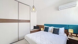 Una camera d'albergo moderna con un letto, un comodino, una lampada, un armadio e un condizionatore d'aria.