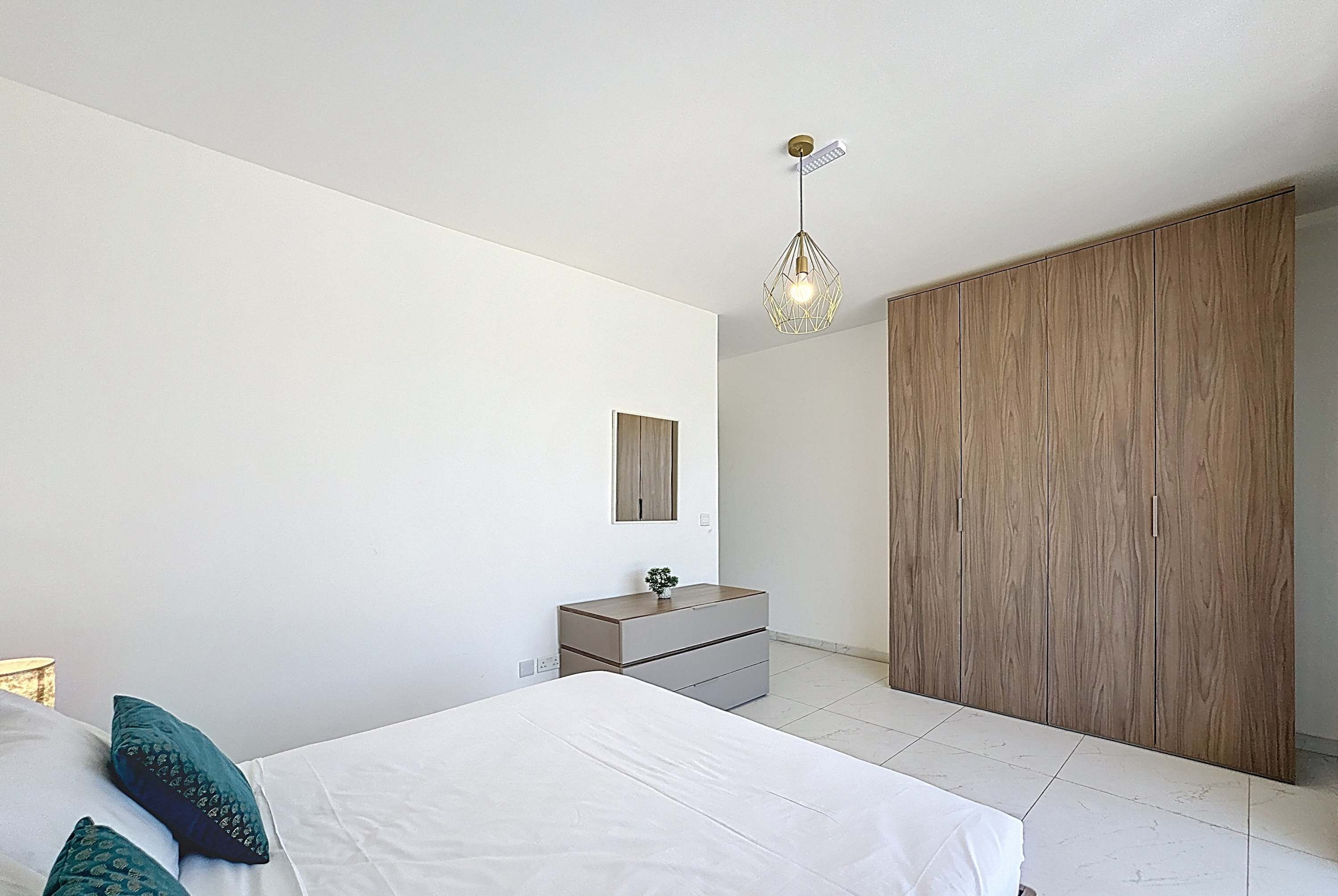 Une chambre à coucher moderne, comprenant un lit, une commode, un miroir et une armoire.