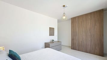 Une chambre à coucher moderne, comprenant un lit, une commode, un miroir et une armoire.