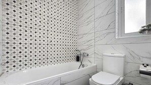 Un bagno con vasca, servizi igienici e una finestra.