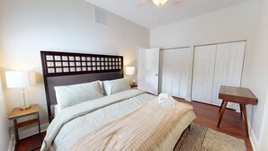 Ein Schlafzimmer mit Bett, Nachttischen, Lampe, Kleiderschrank und Deckenventilator.