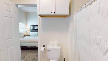 Een badkamer met toilet, douchegordijn en raam.