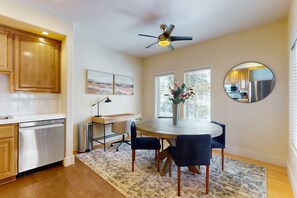 A modern kitchen with wooden cabinets, a dishwasher, a round dining table with chairs, a ceiling fan, and a large mirror. - Conveniently located townhome with kitchen, kitchenette, balcony & fireplace (Bend)