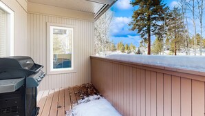 Katettu ulkotila, jossa on grilli, ikkuna ja näkymä puihin ja lumelle.
