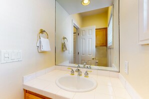 A bathroom with a white sink, three faucets, a mirror, and a towel rack. - Conveniently located townhome with kitchen, kitchenette, balcony & fireplace (Bend)