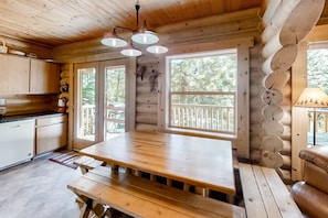 A wooden cabin interior with a large dining table, wooden cabinets, and large windows. - Custom-built log home with gas grill, free WiFi, deck, and private location (Joseph)