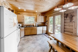 A wooden cabin interior with a kitchen, dining area, and large windows. - Custom-built log home with gas grill, free WiFi, deck, and private location (Joseph)