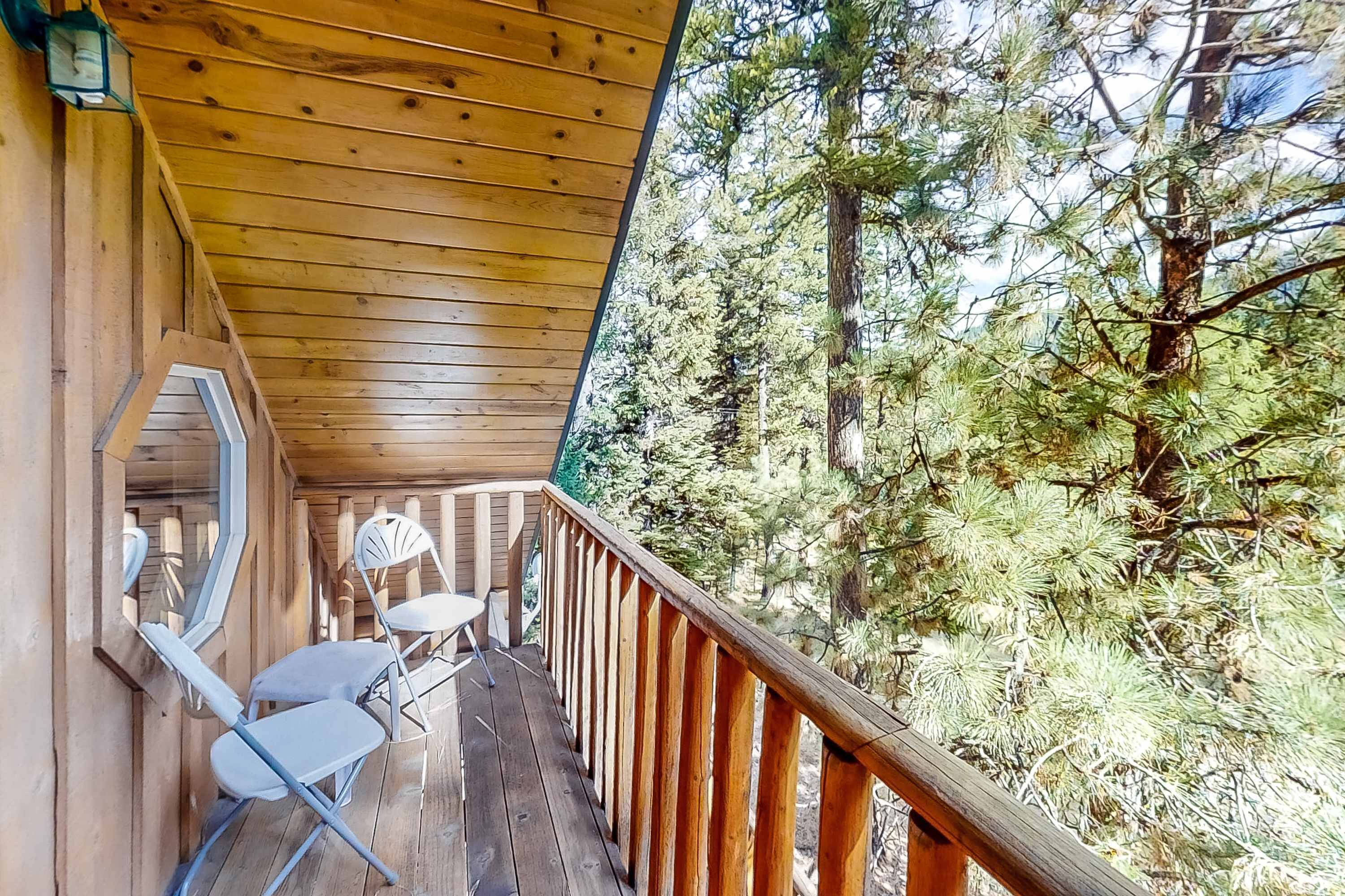 Eine Holzterrasse mit Geländer, Stühlen und einem Tisch.