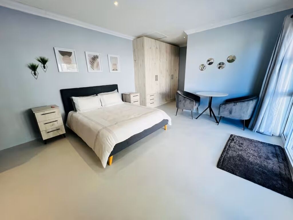 A bedroom with a bed, bedside table, wardrobe, and a small desk with a chair.