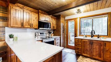 A kitchen with wooden cabinets, a white countertop, a microwave, a stove, and a sink.