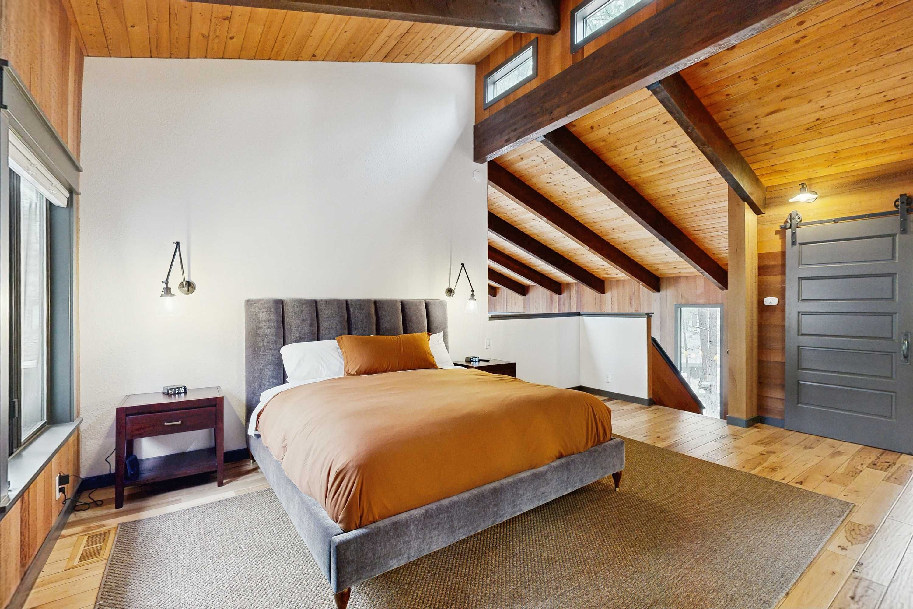 A bedroom with a bed, bedside tables, a window, and a door.