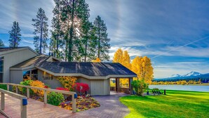 A lodge with a wooden deck, a covered entrance, and a view of a lake and mountains. - Spacious family friendly home with fireplace, full kitchen, deck, grill & WIFI (Black Butte Ranch)