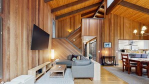 A modern interior with a wooden interior, a sofa, a dining table, and a staircase. - Spacious family friendly home with fireplace, full kitchen, deck, grill & WIFI (Black Butte Ranch)