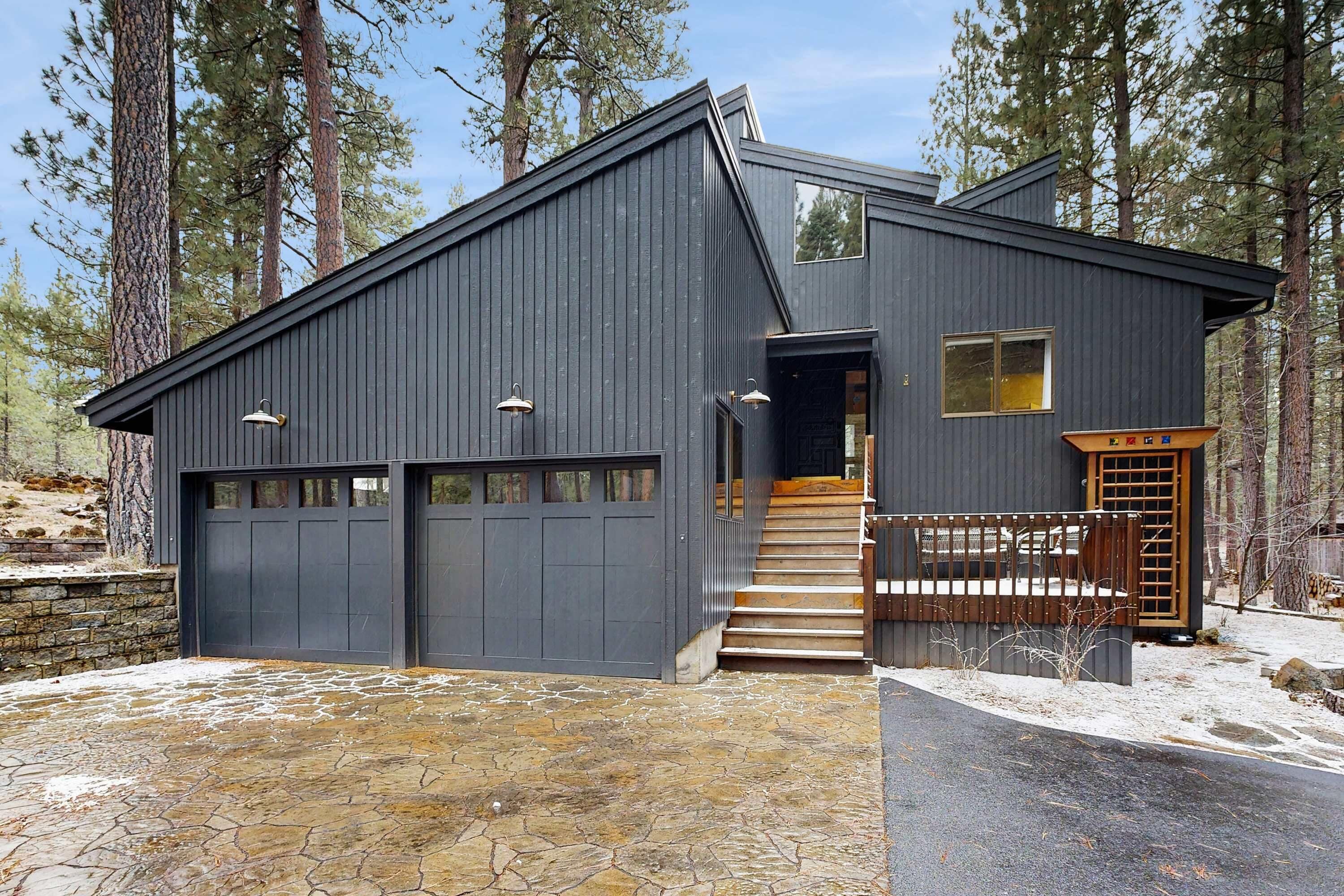 A modern two-story house with a garage, a staircase leading to the second floor, and a stone-paved driveway.
