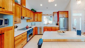 A modern kitchen with wooden cabinets, stainless steel appliances, and a central island. - Ocean view home withhuge deck & yard, hot tub, firepit & game room - dogs OK (Newport)
