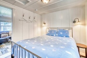 Un dormitorio con una cama, un ventanal, una lámpara colgante e iluminación empotrada en la pared.