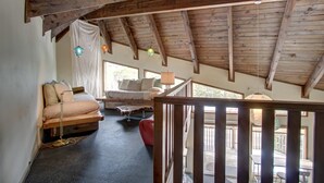 Ein Schlafzimmer im Loft-Stil mit schrägem Dach, einem Bett, einem kleinen Tisch und einem Fenster.