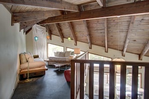 A loft-style bedroom with a sloped ceiling, a bed, a small table, and a window.