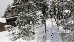 Eine mit Schnee bedeckte Holztreppe führt zu einem Gebäude mit einem Balkon.