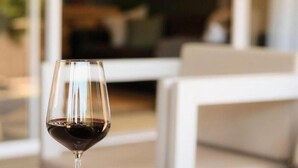 A wine glass with a dark liquid, likely wine, in a modern interior setting with white furniture. - Rissie's 3 Bedroom Apartment (Cape Town)