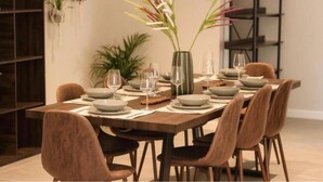 A dining table set with plates, glasses, and a vase with flowers. - Rissie's 3 Bedroom Apartment (Cape Town)