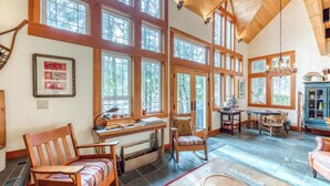 Une pièce spacieuse avec de grandes fenêtres, un bureau en bois, une chaise, une table à manger et une cheminée.
