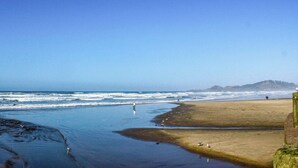 A beach with waves, a sandy shore, and a distant mountain. - Modern Beach House with Partial Ocean Views - Walk to Nye Beach & Attractions (Newport)