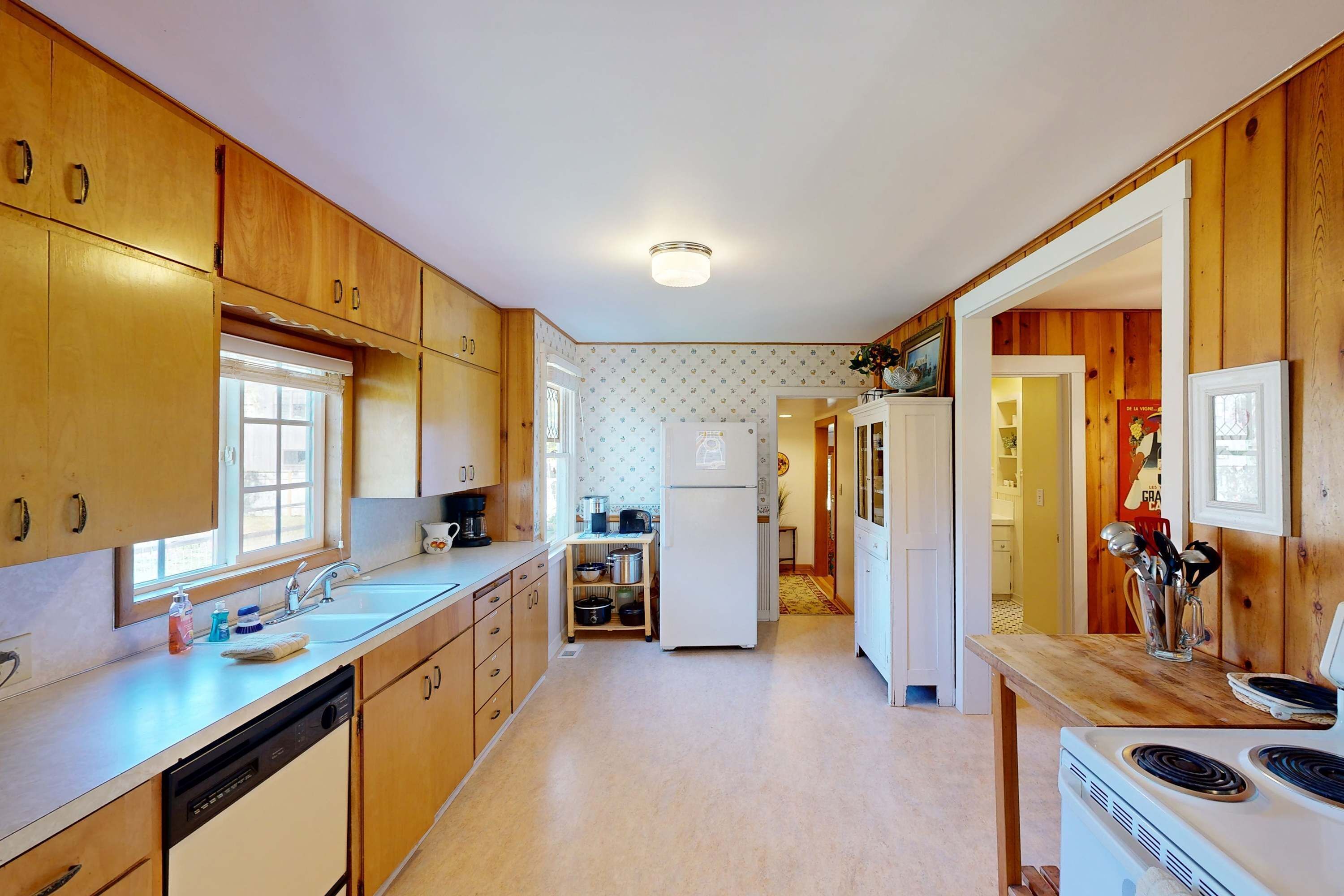 Una cocina con armarios de madera, lavavajillas, refrigerador y estufa.