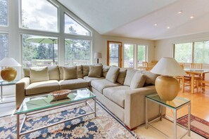 Ein geräumiges Wohnzimmer mit Ecksofa, Glastisch und Essbereich mit Tisch und Stühlen.